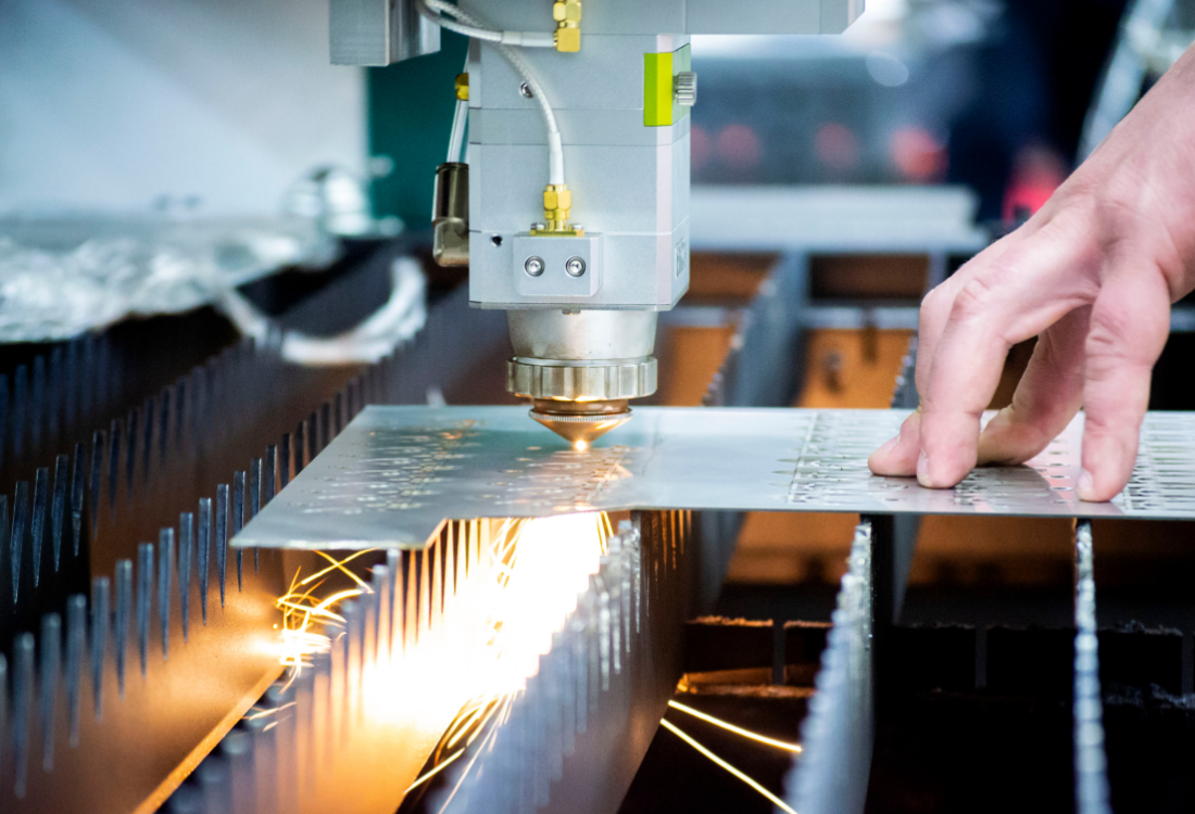 Laser cutting machine processing sheet metal with sparks flying during fabrication.