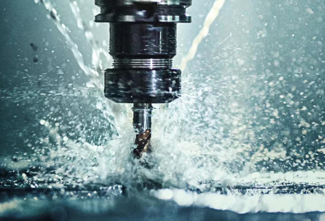 Close-up of a CNC machine performing precision surface finishing with coolant spray. Advanced surface finishing solutions reduce friction, prevent wear, and minimise machine downtime for improved manufacturing efficiency.