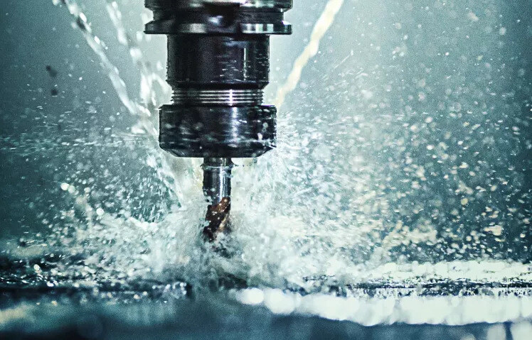 Close-up of a CNC machine performing precision surface finishing with coolant spray. Advanced surface finishing solutions reduce friction, prevent wear, and minimise machine downtime for improved manufacturing efficiency.